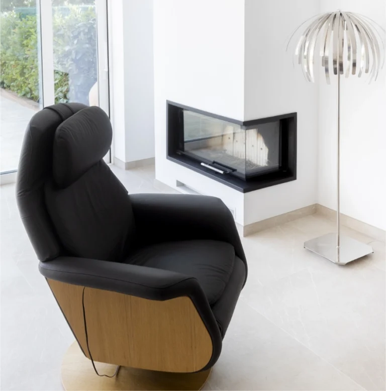 Salón con chimenea y butaca junto al ventanal