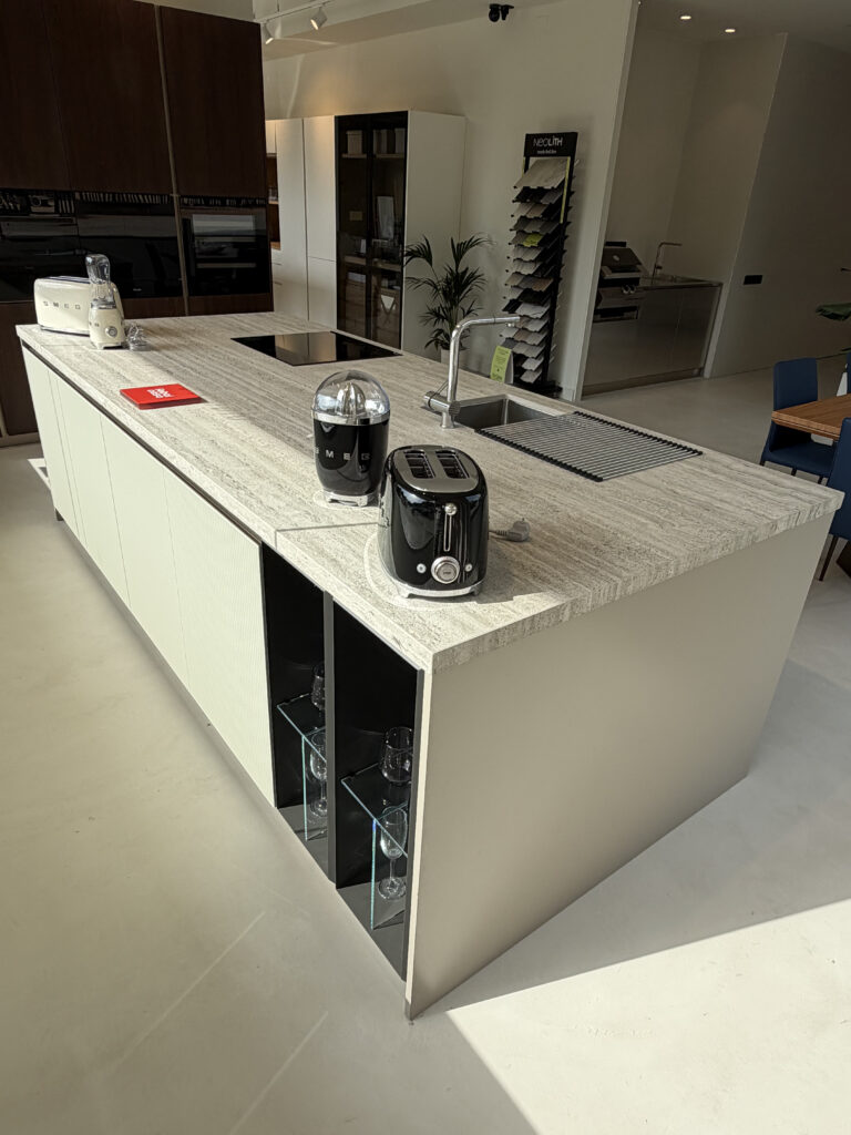 Isla de cocina con placa de inducción y electrodomésticos Smeg en el showroom de Amplitud Studio