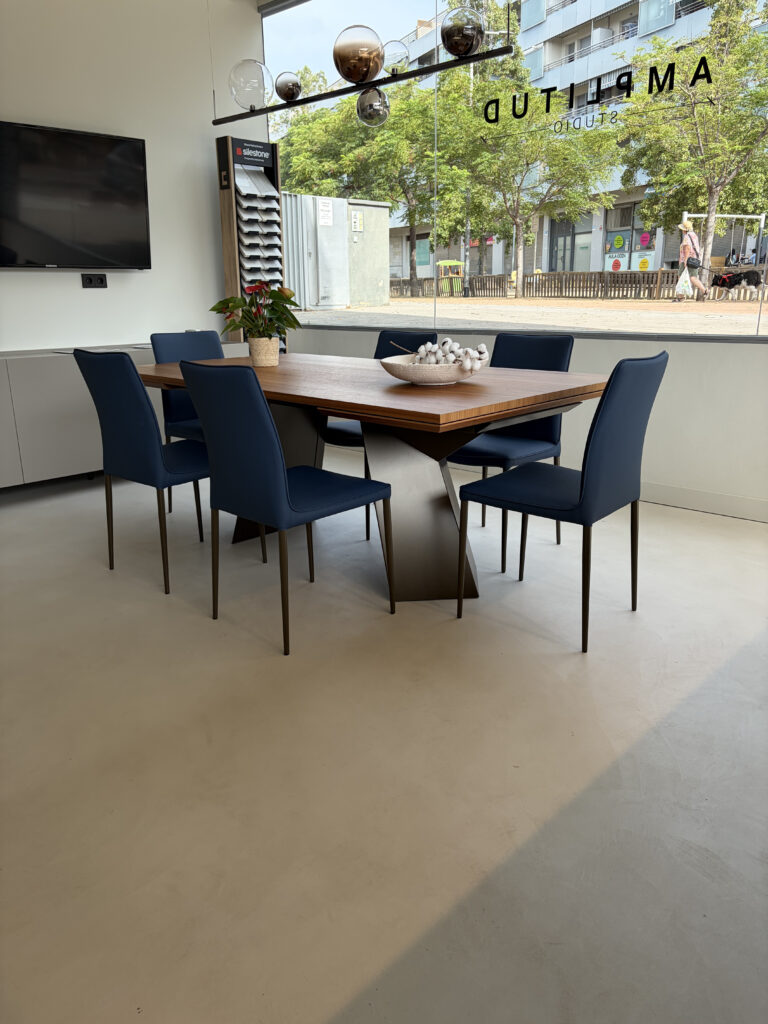 Zona de comedor con mesa de madera y sillas en el showroom de Amplitud Studio