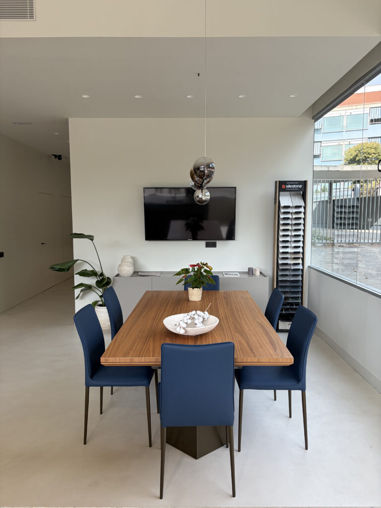 Zona de comedor con mesa de madera y sillas en el showroom de Amplitud Studio
