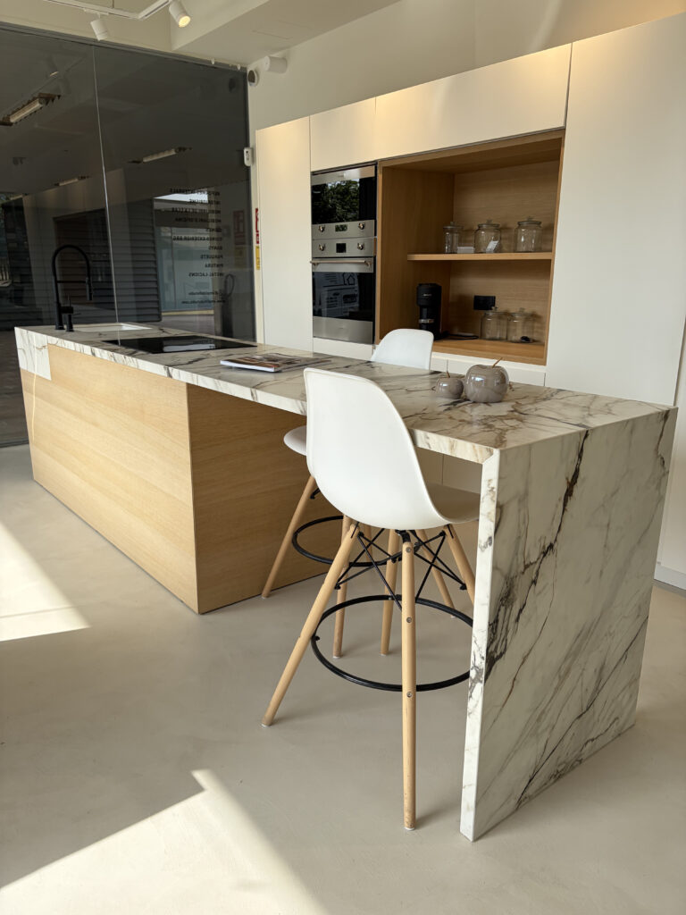 Isla de cocina con encimera de mármol y madera en el showroom de Amplitud Studio