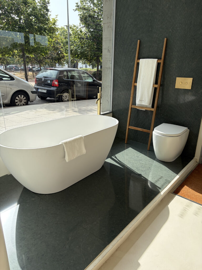 Bañera exenta y mármol verde en el showroom de baños de Amplitud Studio